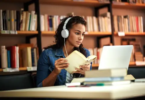 Girl studying with a book and laptop